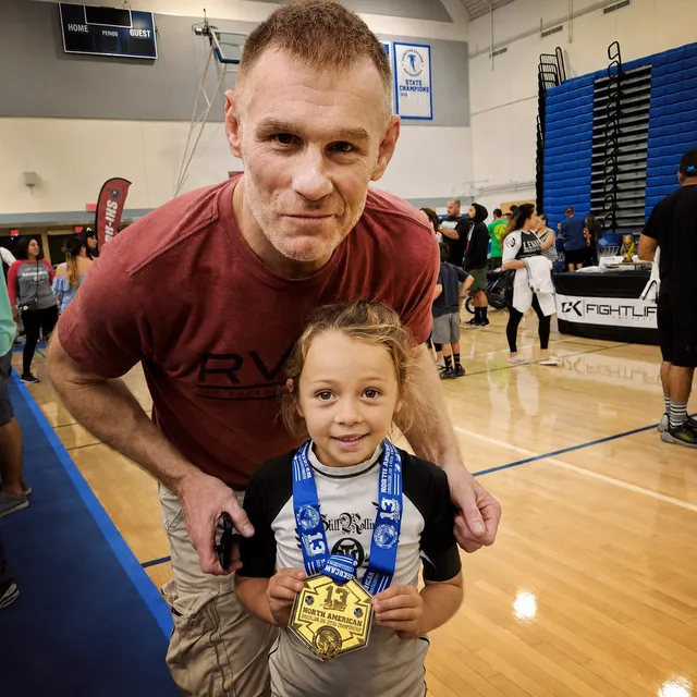 Professor James Boran with a young Boran student and her gold medal at a Brazilian Jiu-Jitsu tournament